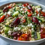 A vibrant bowl of Mediterranean Pearl Couscous topped with crumbled feta and fresh parsley, perfect for a healthy vegetarian lunch or potluck side.