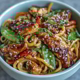 A colorful Sesame Chicken Noodle Bowl featuring stir-fried chicken, fresh veggies, and chewy noodles tossed in a sweet-savory sesame sauce.  