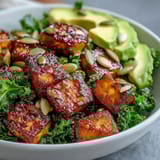 Protein-packed tofu and kale bowl topped with fresh avocado, green onions, and a sprinkle of nutritional yeast for extra flavor.  