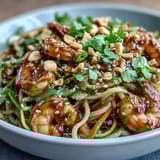 Tender rice noodles tossed with crisp zucchini, carrots, and juicy shrimp, all coated in a savory Asian-inspired sauce and garnished with herbs.