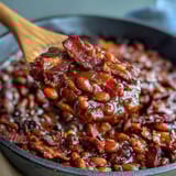 Savory baked beans with bacon and brown sugar, bubbling hot from the oven with a glossy, smoky-sweet glaze.