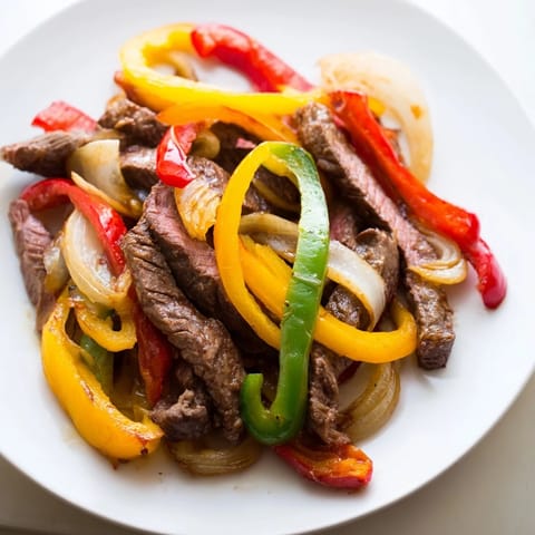 A close-up of vibrant steak fajitas with colorful bell peppers and sizzling beef for a flavorful dinner.