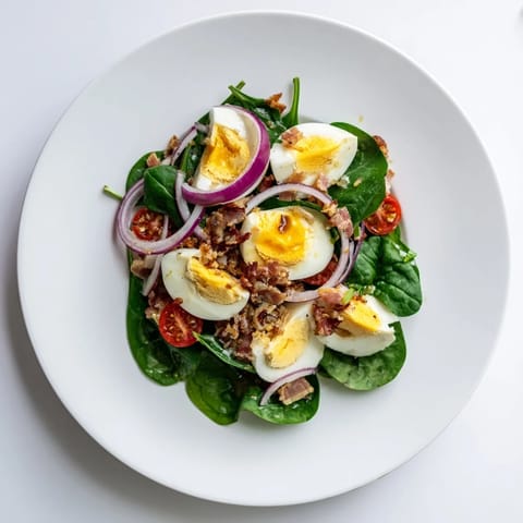 This spinach salad with bacon features crumbled bacon, juicy tomatoes, and a honey-mustard vinaigrette.