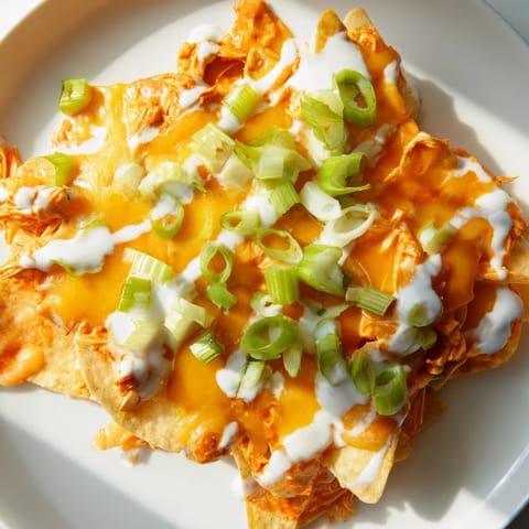 Golden baked Buffalo Chicken Nachos with melted cheddar and Monterey Jack, drizzled with cool ranch and topped with fresh green onions for a zesty game day snack.