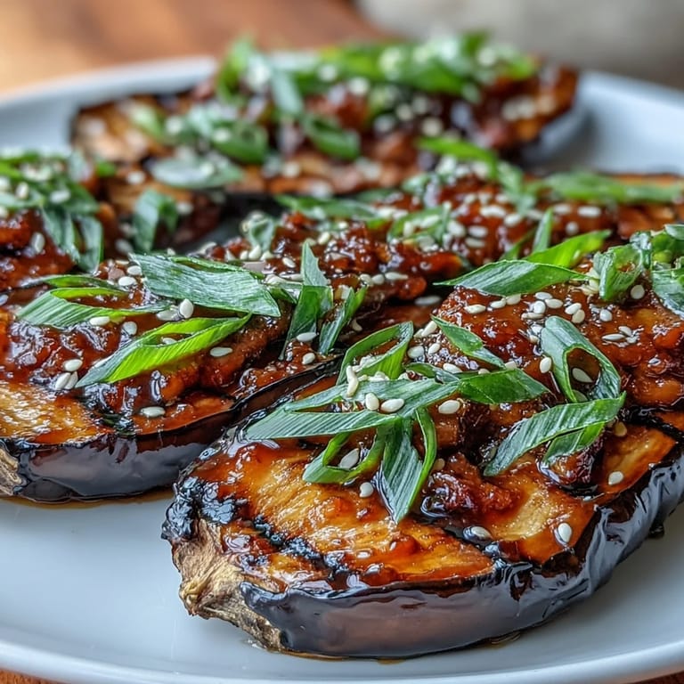 Umami-rich miso glazed eggplant with glossy glaze, garnished with scallions and sesame, perfect over steamed rice.