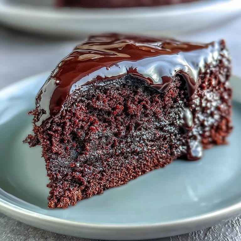 Ultra-moist Easy Chocolate Fudge Cake with a glossy chocolate ganache coating, sliced open to show a dense, fudgy interior.