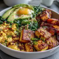 Wholesome vegan breakfast bowl with savory tofu scramble, roasted sweet potatoes, and fresh avocado slices.  