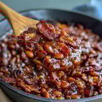 Savory baked beans with bacon and brown sugar, bubbling hot from the oven with a glossy, smoky-sweet glaze.